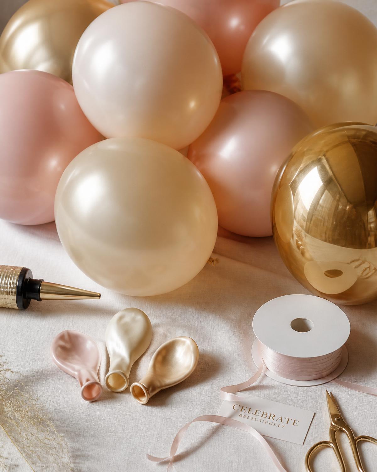 Premium blush, champagne and gold latex balloons with decorating tools on ivory linen